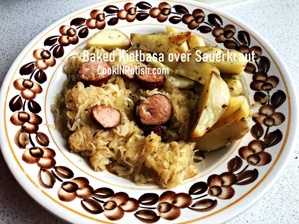 baked kiełbasa over Sauerkraut served on a folk plate.