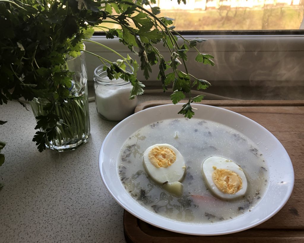 Polish sorrel soup served in a plate with hard boiled egg.