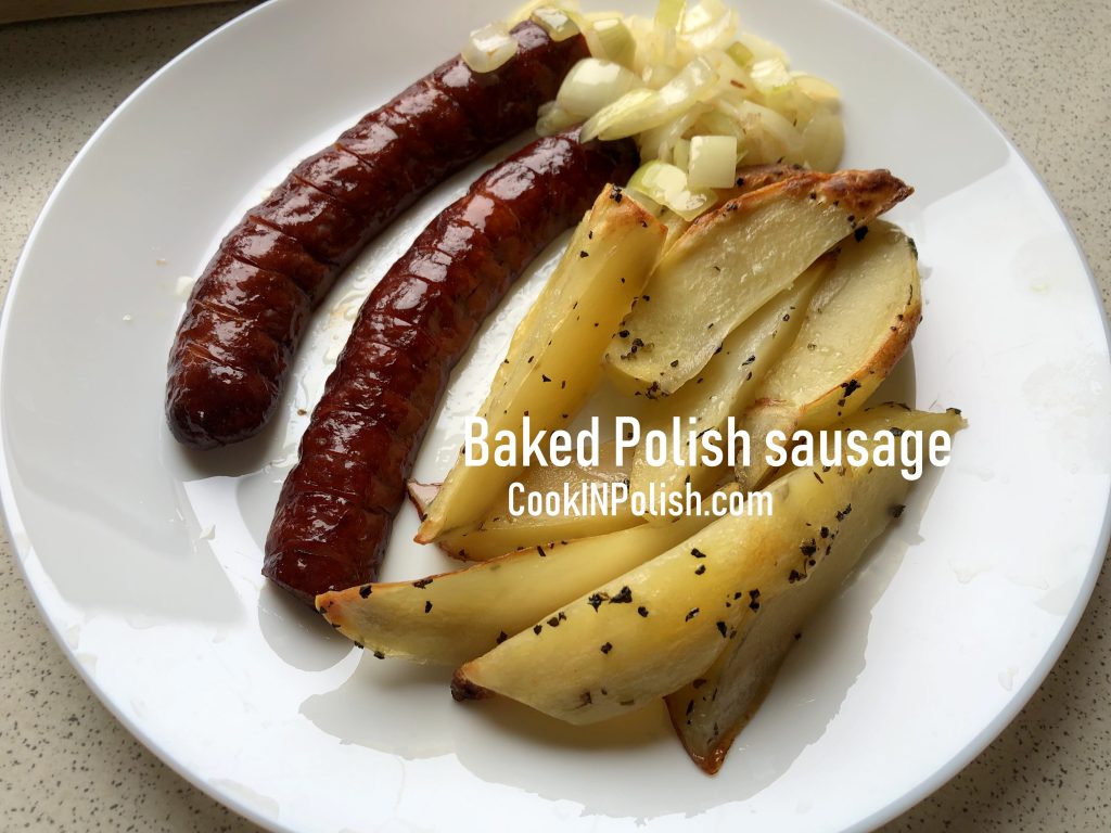 Polish baked sausage with onions and baked potatoes on the plate.