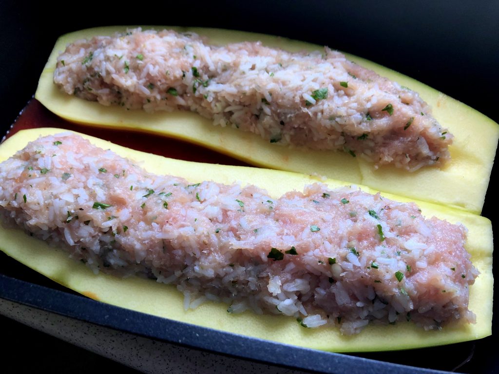 Zucchini ready to be baked: stuffed with raw meat filling.