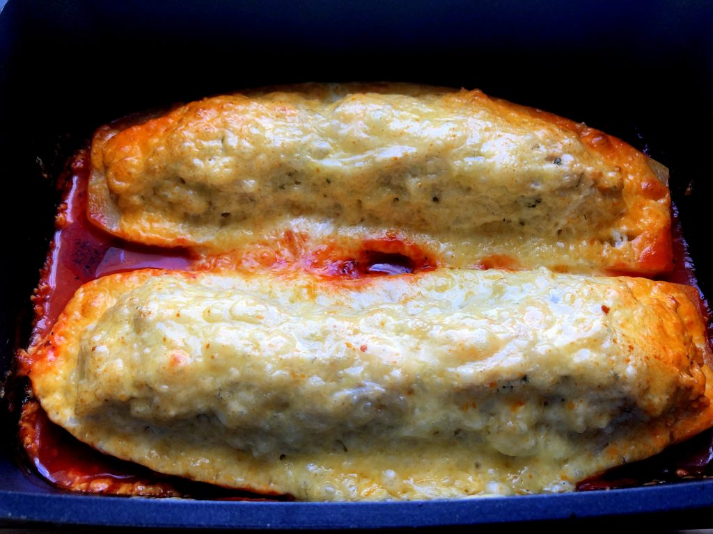 Ready baked Polish stuffed zucchini under crispy topping in the baking dish.