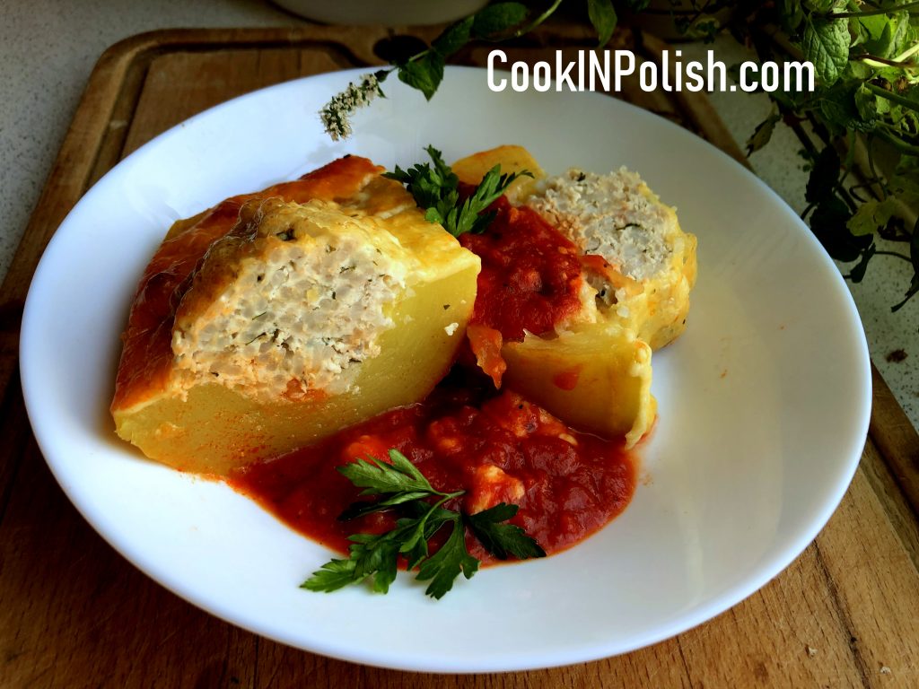 Ready baked Polish stuffed zucchini on the plate with tomato sauce.