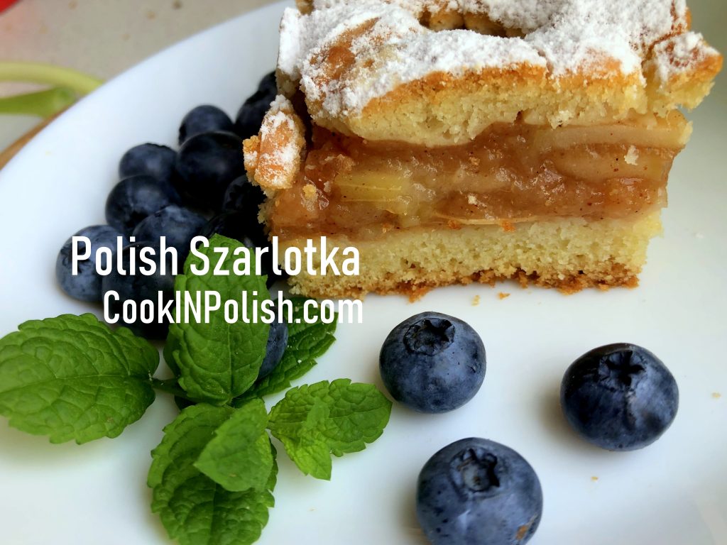 Polish apple pie served on the plate with blueberries and mint.