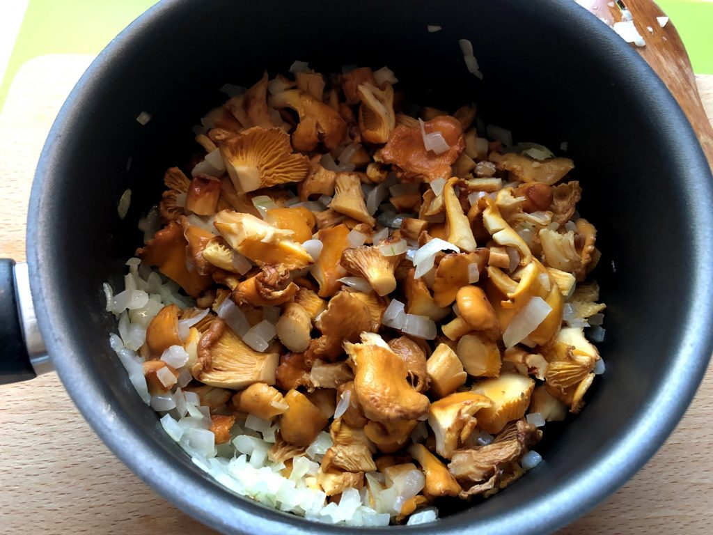 Mixed Chanterelles frying on the pan with onions.