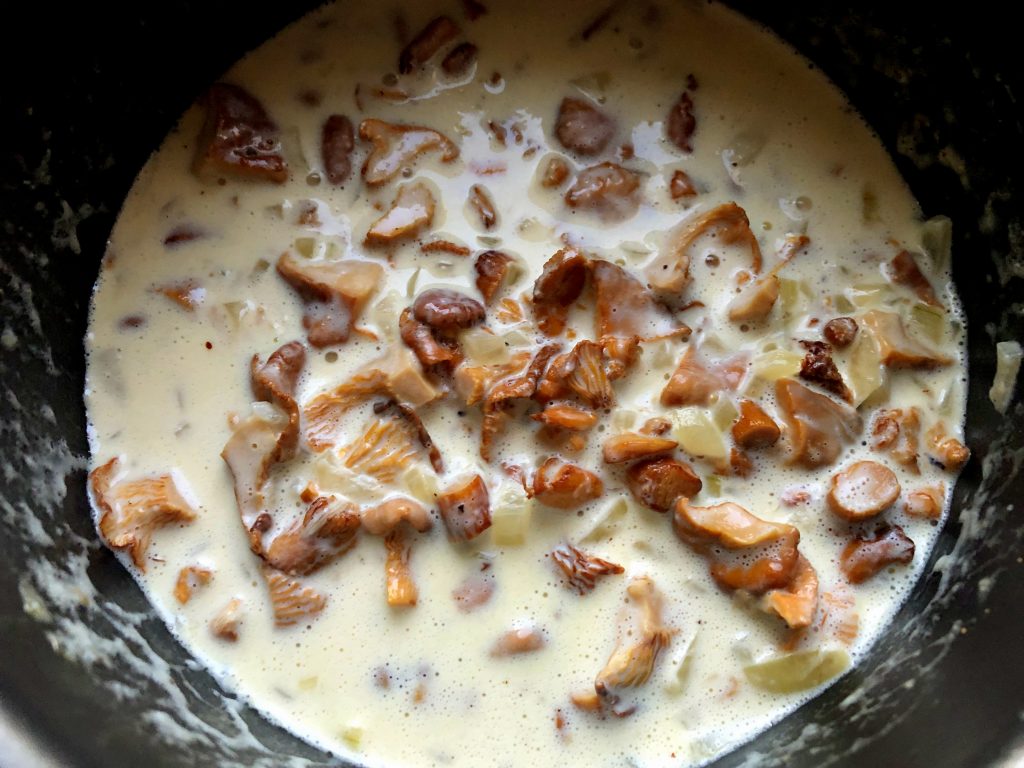 Chanterelles frying on the pan with onions and sweet cream.