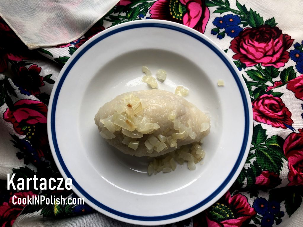 Kartacze Polish Potato Dumplings served on a plate with sauteed onions.