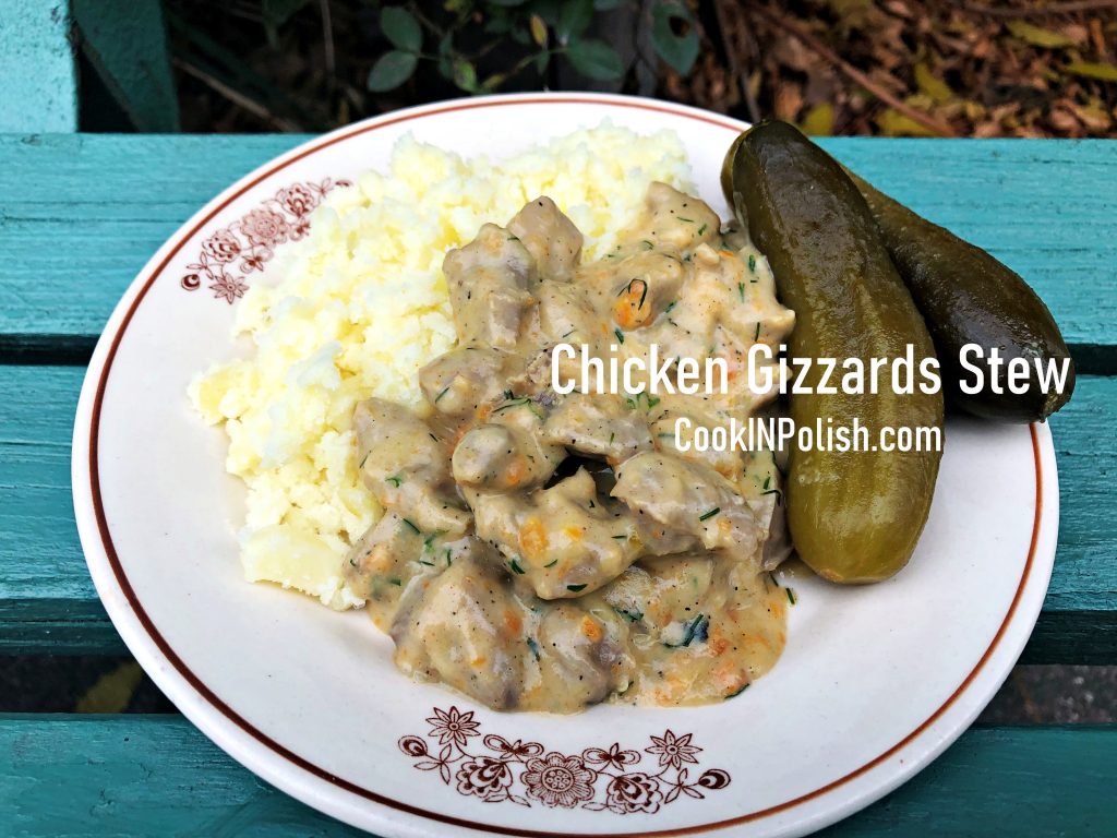 Chicken Gizzards Stew served on the plate with boiled potatoes and gherkins.