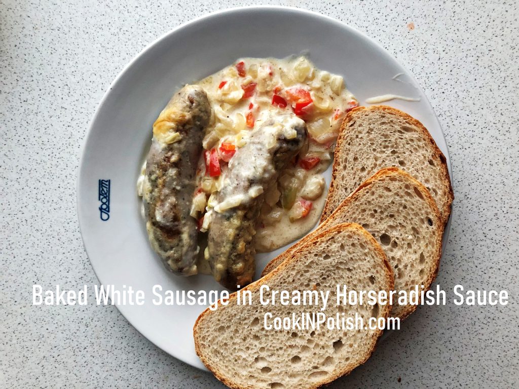 Baked white raw sausage in creamy horseradish sauce served on a plate with bread